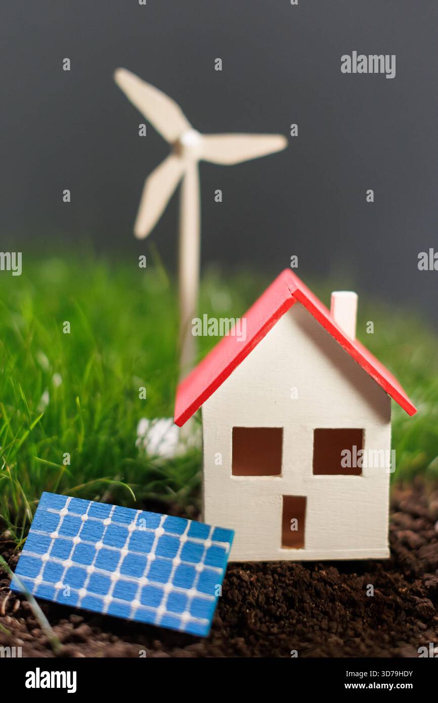 Casa in miniatura circondata da fonti di energia rinnovabili Foto Stock