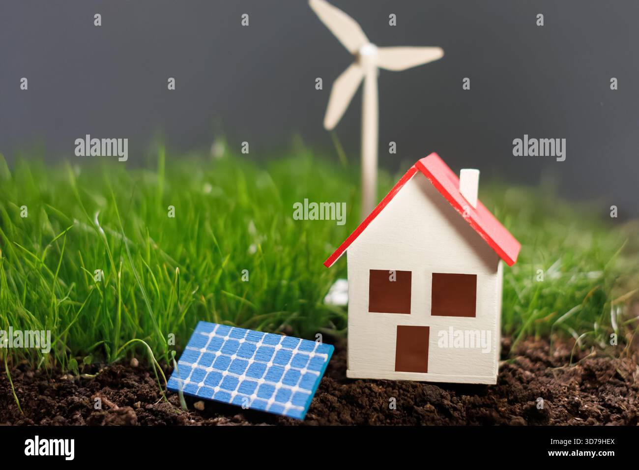 Modello che rappresenta l'energia rinnovabile con una casa, una turbina eolica e un pannello solare su sfondo neutro Foto Stock