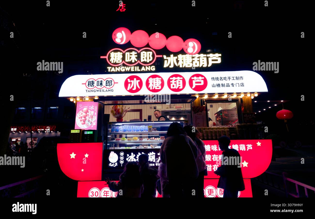 Gli amanti dello shopping notturno di Pechino si allineano al luminoso chiosco tangweilang Foto Stock