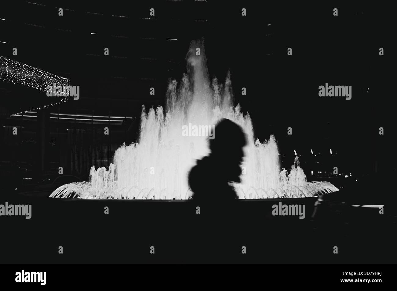 Silhouette di un attraversamento passante di fronte ad una fontana luminosa dell'hotel a Pechino Foto Stock