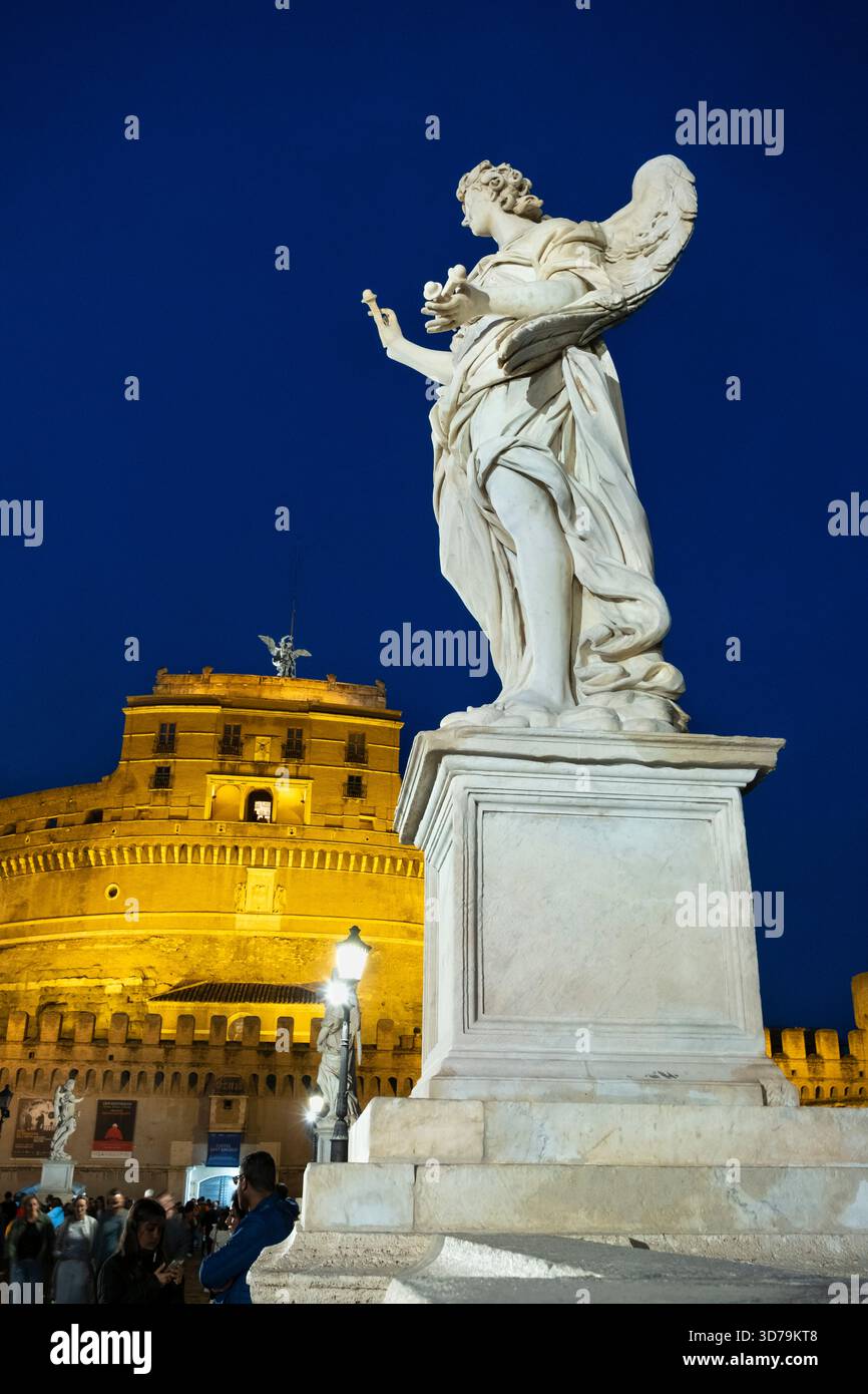 Statue di angeli illuminate di notte sul Ponte Sant'Angelo, con sullo sfondo Castel Sant'Angelo. Roma, Italia. Foto Stock