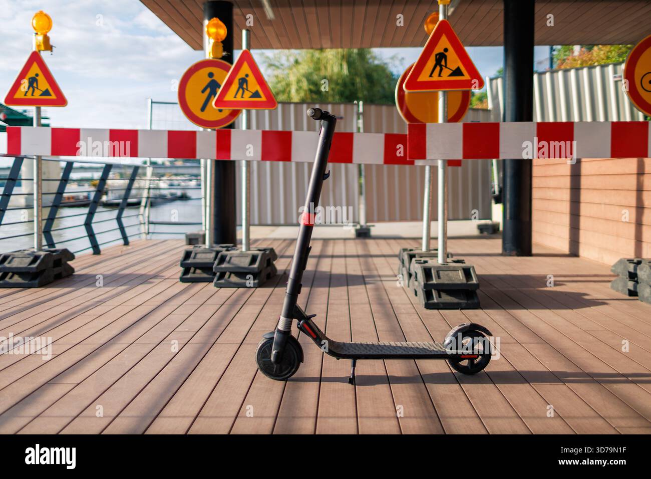 scooter elettrico parcheggiato vicino alla segnaletica stradale e alle barriere Foto Stock