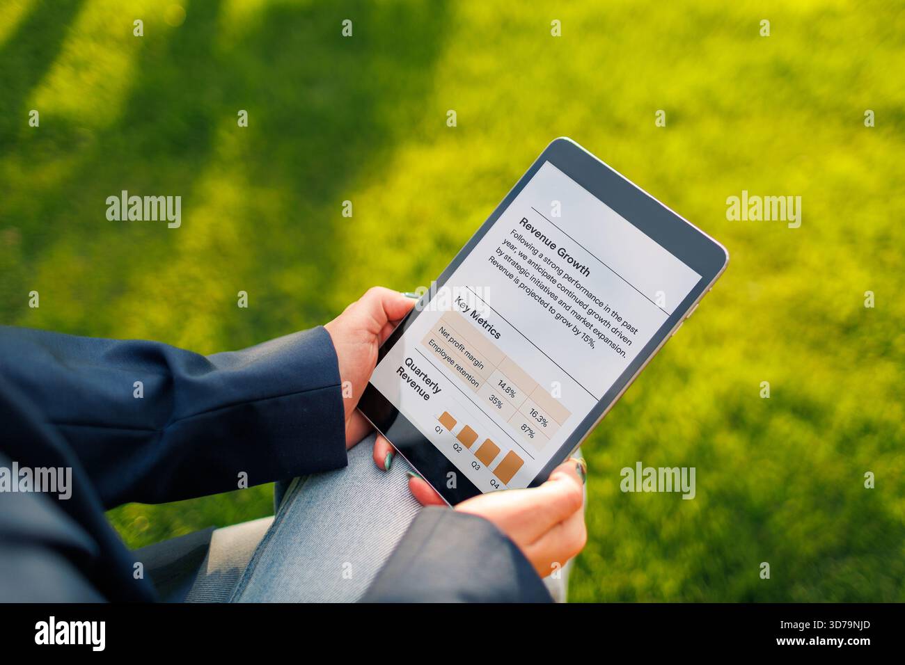 Persona che utilizza un tablet per analizzare i dati di mercato in un ambiente soleggiato all'aperto Foto Stock