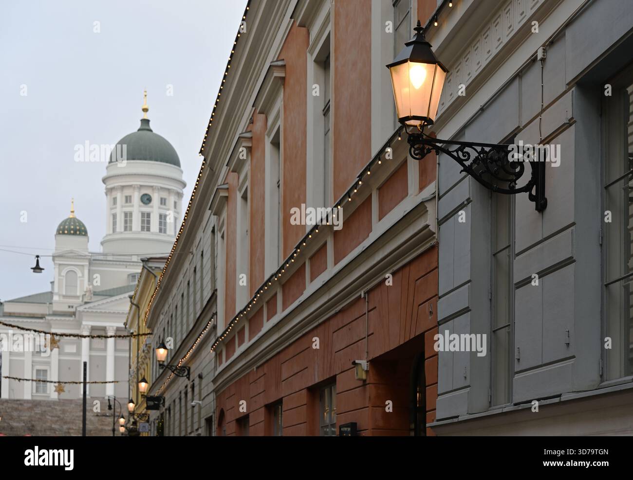 Una suggestiva vista a livello della strada nel centro di Helsinki, caratterizzata da edifici storici adornati da calde luci stradali e decorazioni natalizie Foto Stock