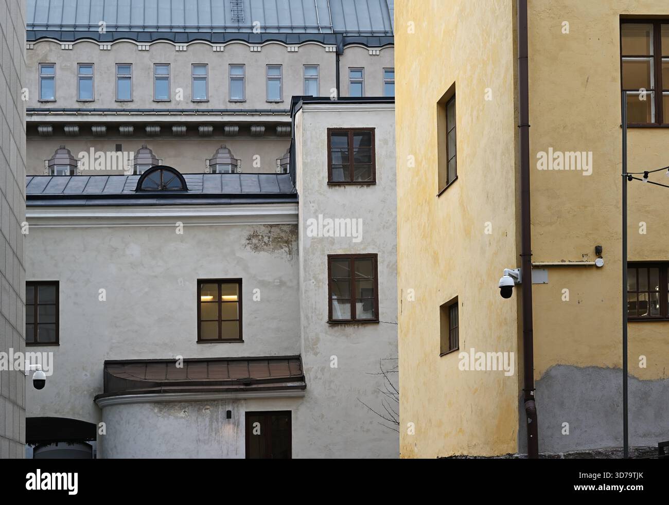 Una tranquilla scena architettonica a Helsinki caratterizzata da un mix di edifici storici nordici con pareti in gesso logore, finestre con cornici in legno e morbidi pastello Foto Stock