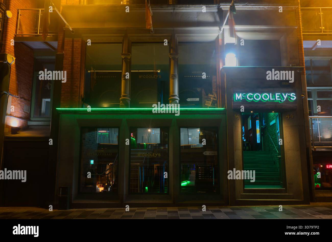 McCooley's Irish bar nel quartiere Cavern di Liverpool di notte. L'entrata è illuminata da una luce verde neon brillante. Foto Stock