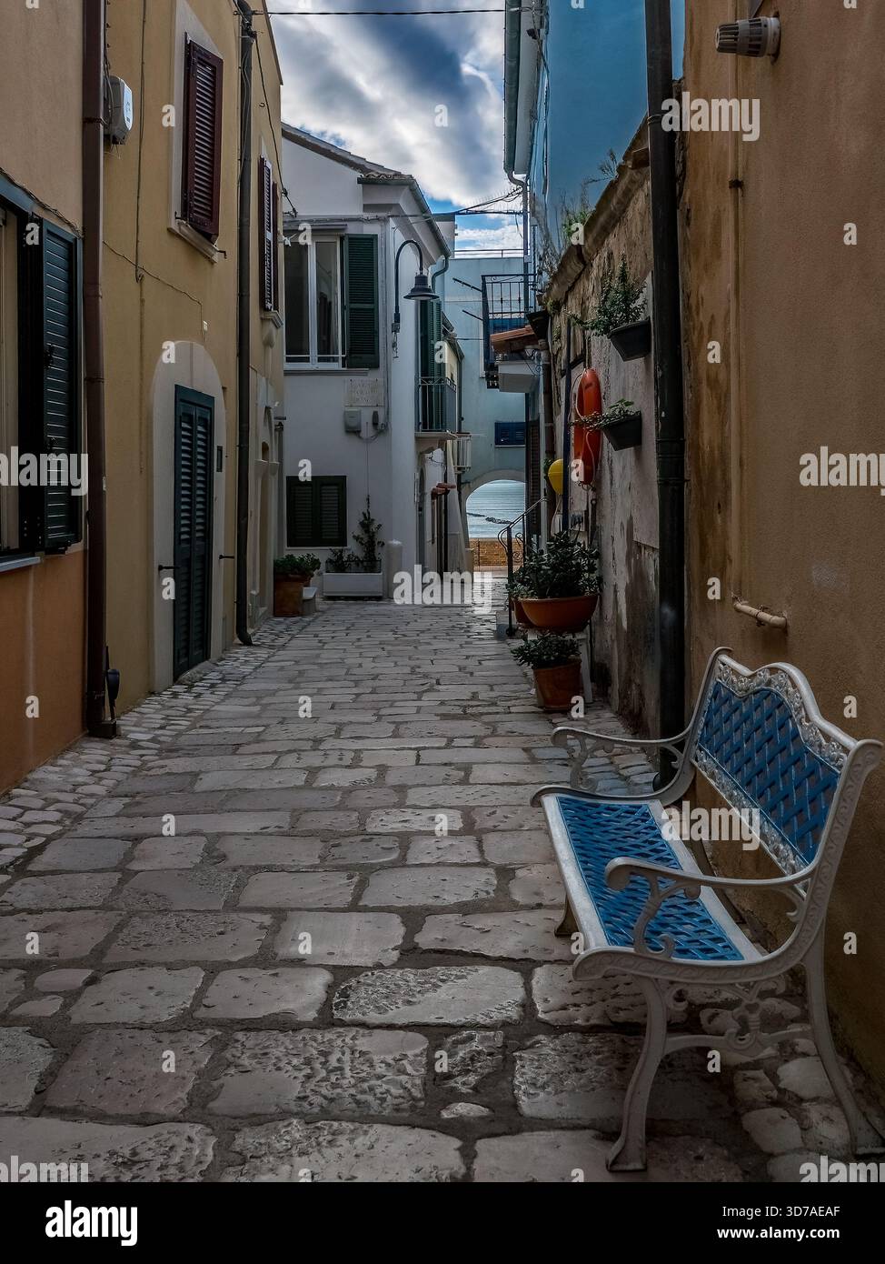 Stretta strada acciottolata nel centro storico di Termoli Italia con panchina blu e bianca Foto Stock