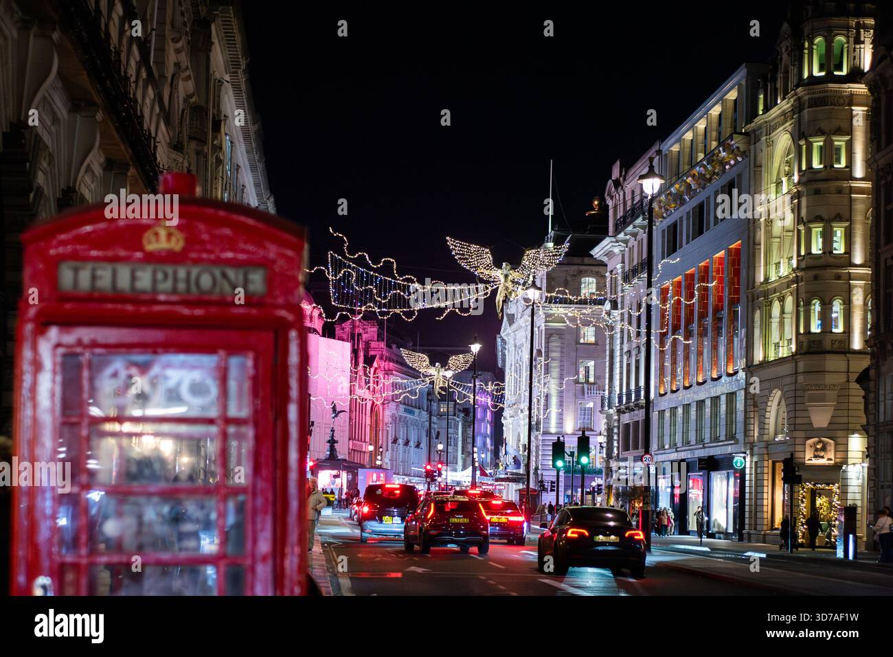 Installazioni illuminate e decorazioni natalizie esposte di notte nel centro di Londra, con semafori e negozi Foto Stock