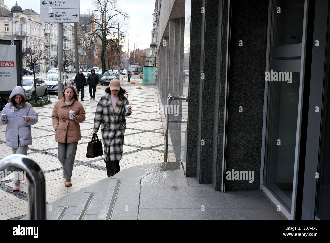 Molte persone si divertono a passeggiare mentre tengono bevande calde in una strada tranquilla. 24 novembre 2025 Kiev, Ucraina Foto Stock