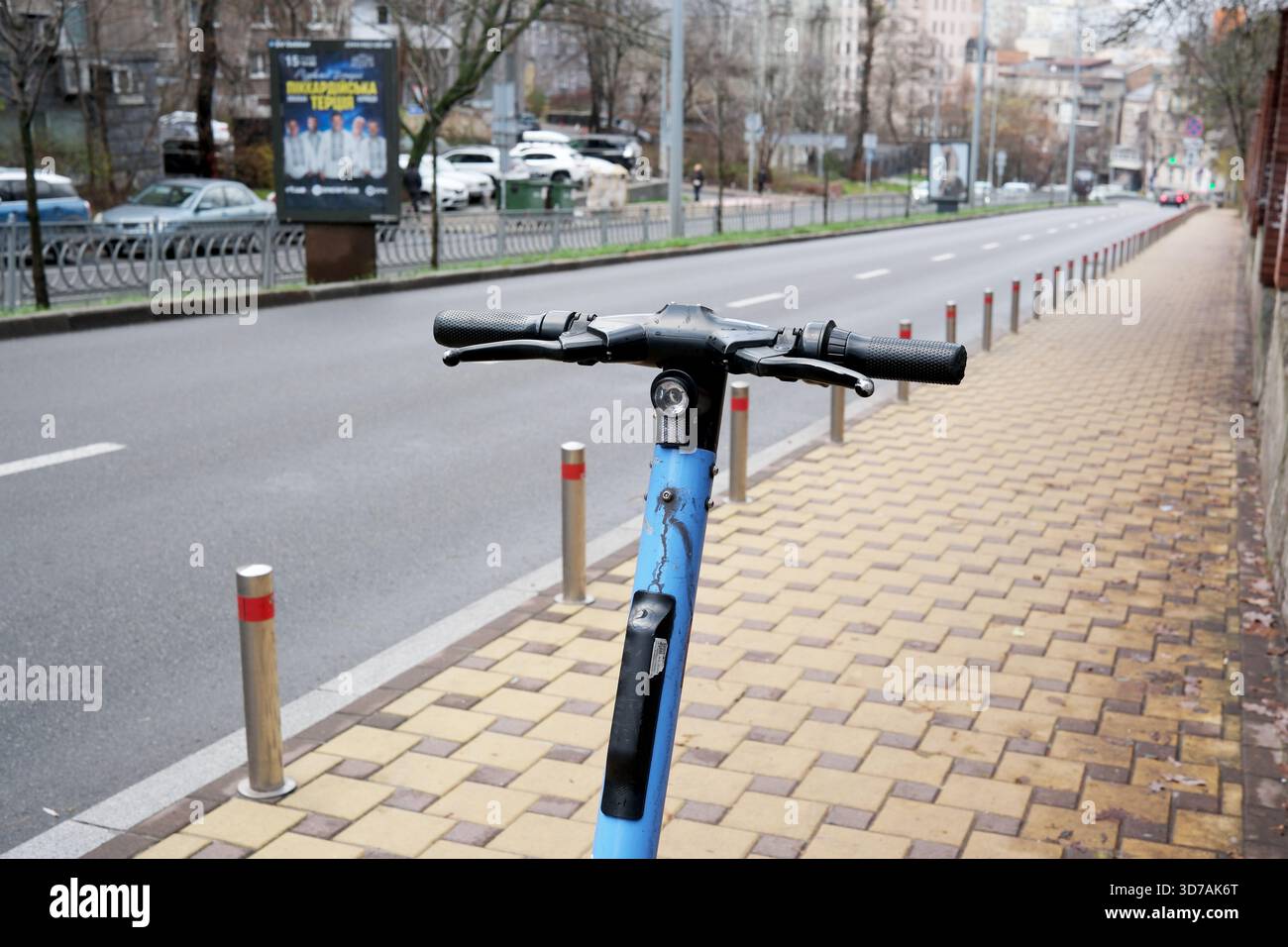 In inverno, uno scooter blu brillante ti aspetta per il tuo prossimo viaggio in una tranquilla strada della città. 24 novembre 2025 Kiev, Ucraina Foto Stock