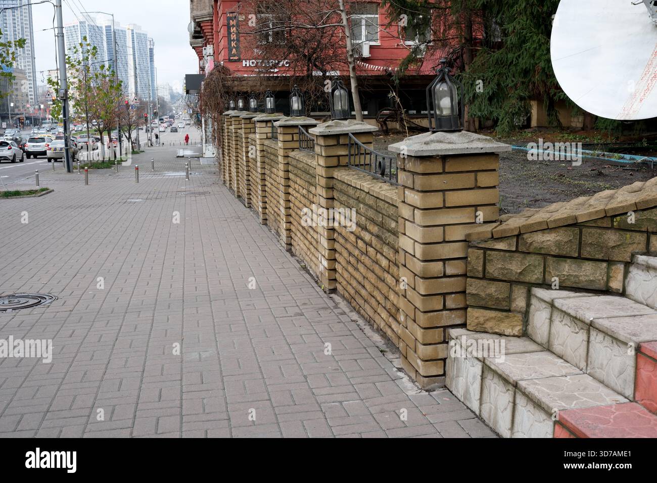 Una tranquilla strada cittadina con un muro di pietra e edifici moderni invita a esplorare. 24 novembre 2025, Kiev, Ucraina, Shevchenko Boulevard Foto Stock