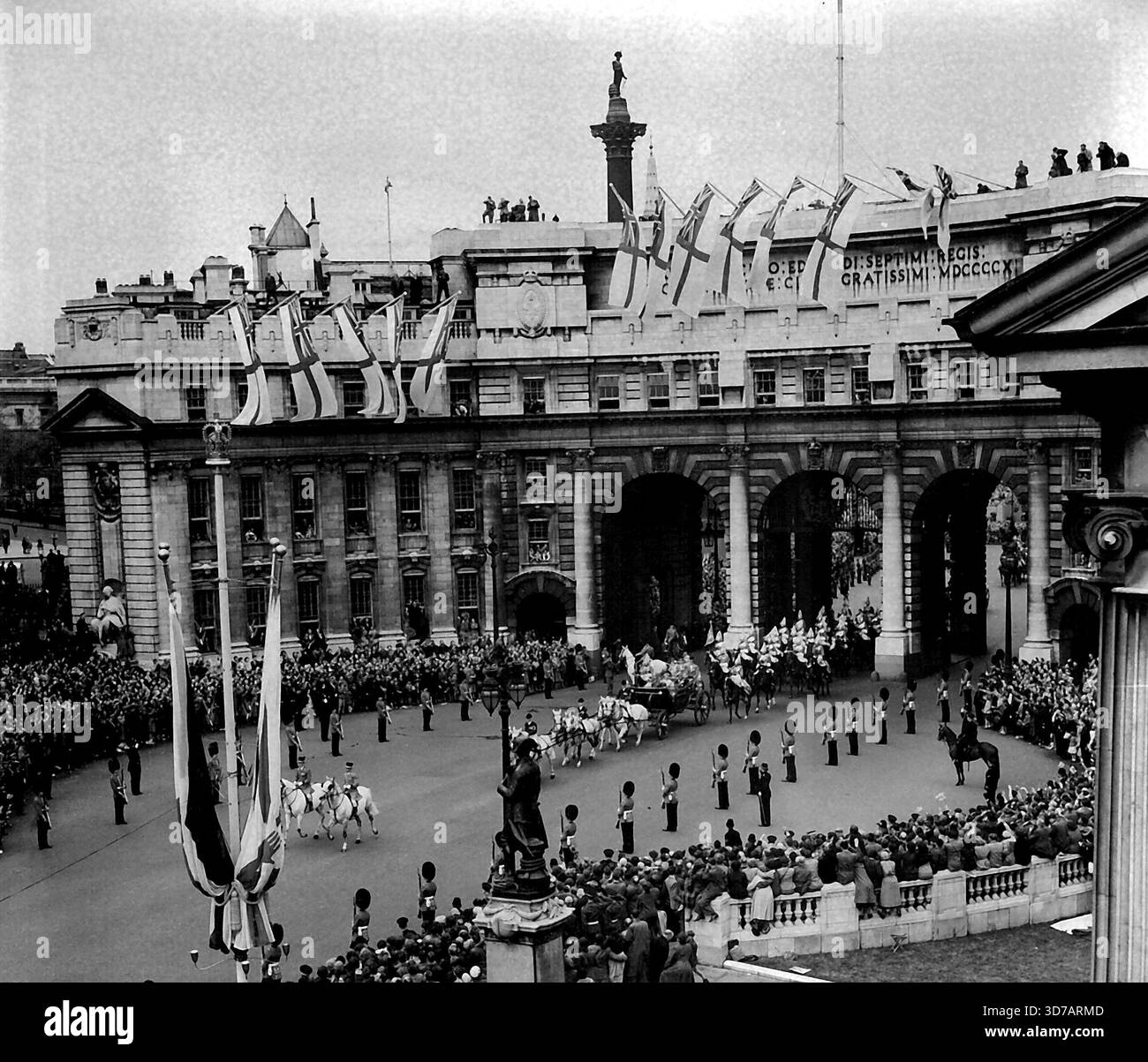 Attraverso l'Admiralty Arch Again Queen's Home Coming - la processione di ritorno reale che passa attraverso l'Admiralty Arch nel Mall durante il suo viaggio attraverso strade affollate da Westminster Pier, Londra, a Buckingham Palace di giorno (sabato). La Regina e il Duca di Edimburgo viaggiano con i loro figli - il Principe Carlo e la Principessa Anna - in un landau di Stato disegnato da sei grigi. La Regina e il Duca avevano raggiunto Londra prima nel giorno dopo essere tornati dal loro tour di sei mesi del Commonwealth. I bambini li avevano accompagnati a casa da Tobruk sullo yacht reale Britannia. 15 maggio 1954. Foto Stock
