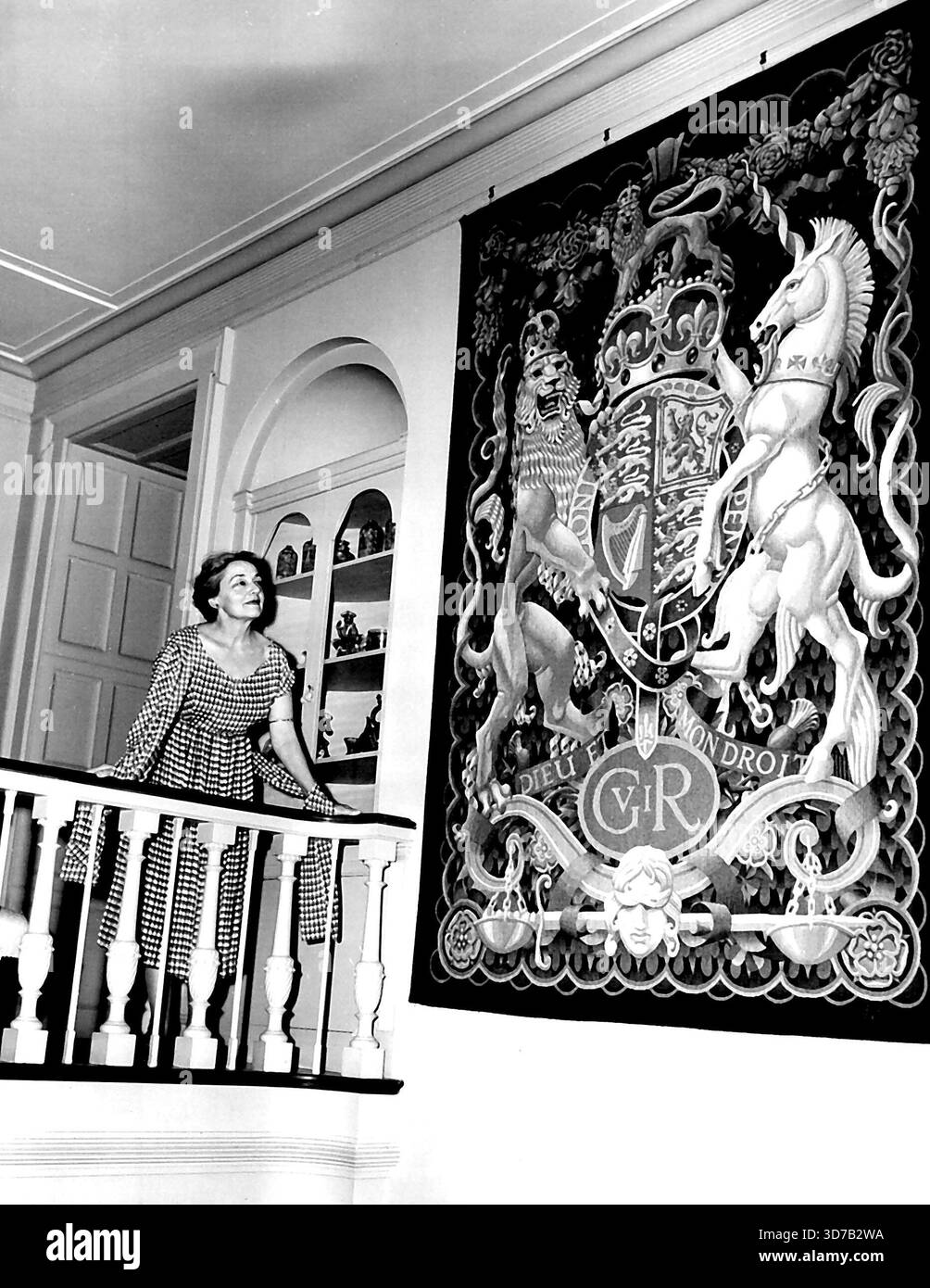 Lo stemma di King è appeso a Wave Hill Lady Dixon, moglie del delegato permanente della Gran Bretagna alle Nazioni Unite, Sir Pierson Dixon, si trova vicino all'arazzo che porta lo stemma di Re Giorgio vi a Wave Hill, la casa di Dixon Riverdale a New York City, 19 ottobre. La regina madre Elisabetta soggiornerà a Wave Hill durante la sua visita a New York dal 26 ottobre al 4 novembre. 19 ottobre 1954. (Foto di Associated Press Photo). Foto Stock