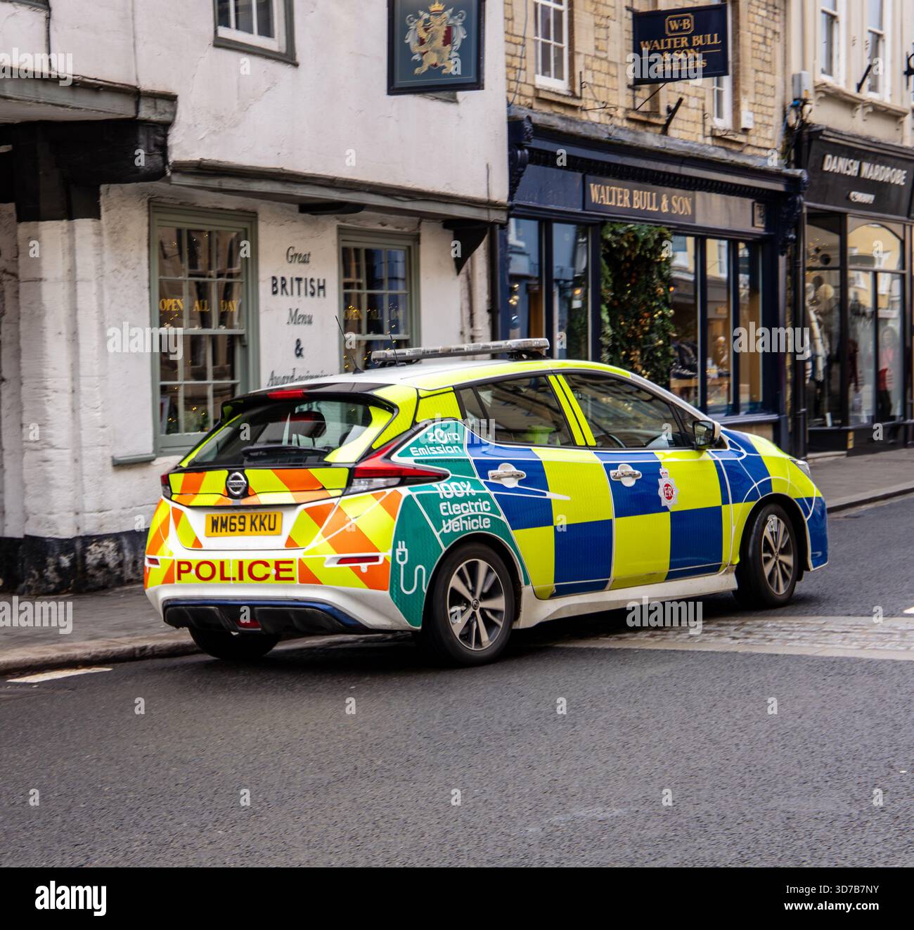 Auto elettrica della polizia britannica parcheggiata lungo una strada vicino ai negozi storici nel centro di Cirencester nel Gloucestershire Foto Stock