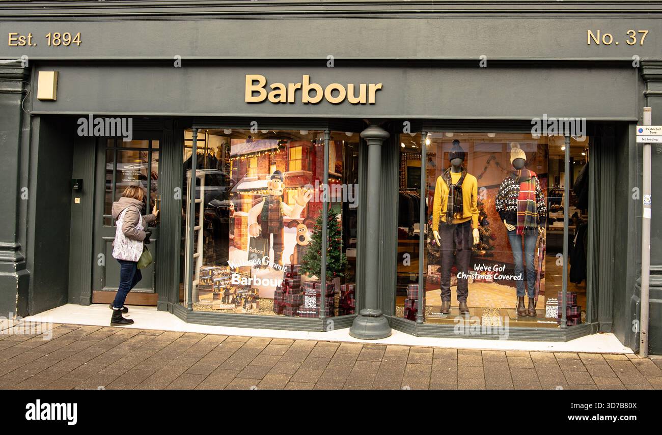 Donna che entra nel negozio di abbigliamento Barbour con vetrine a tema natalizio e manichini vestiti alla moda invernale Foto Stock