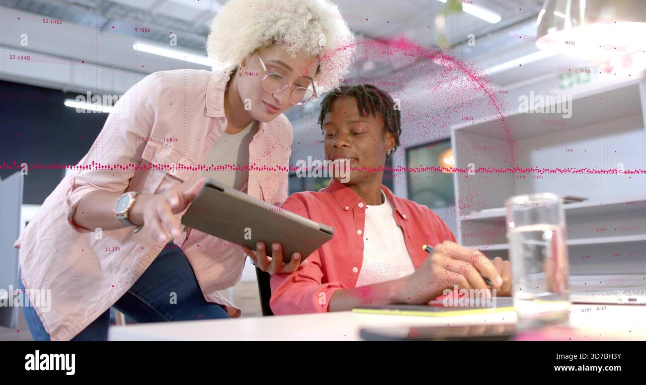 Camicia rosa donna pendente e camicia in corallo uomo che discutono di tablet alla scrivania con sovrapposizione dati Foto Stock