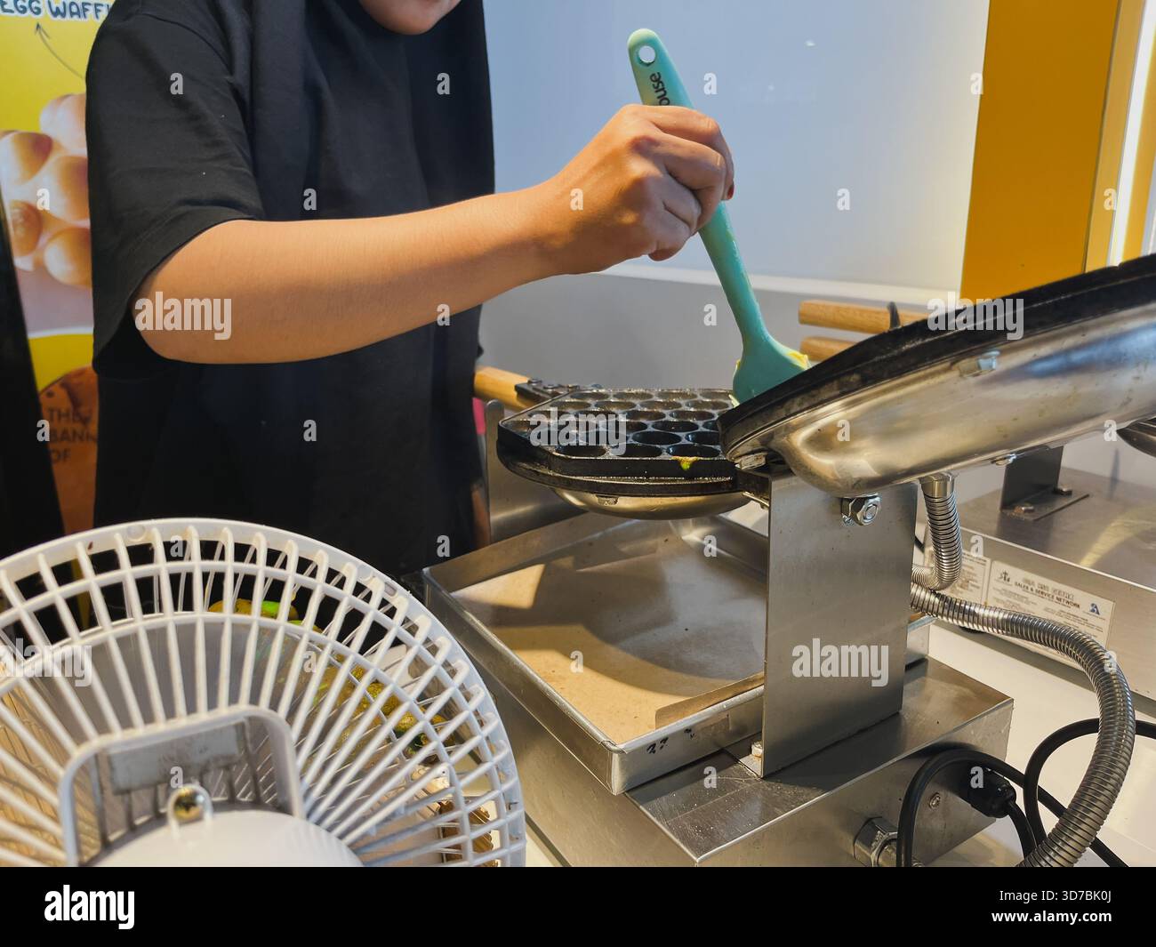 Balikpapan, Indonesia - 16 novembre 2025 Una persona con una t-shirt nera sta usando una spazzola di silicone azzurro per applicare la pastella o l'olio alla muffa emisferica Foto Stock