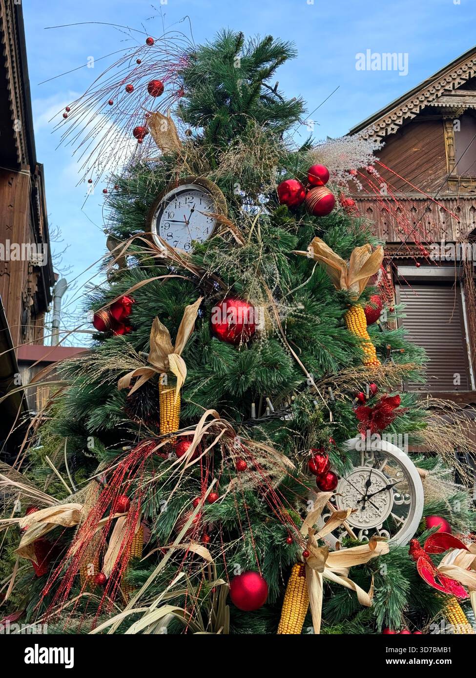 Albero di Natale decorato con mais, orologio antico e palline rosse lucenti Foto Stock