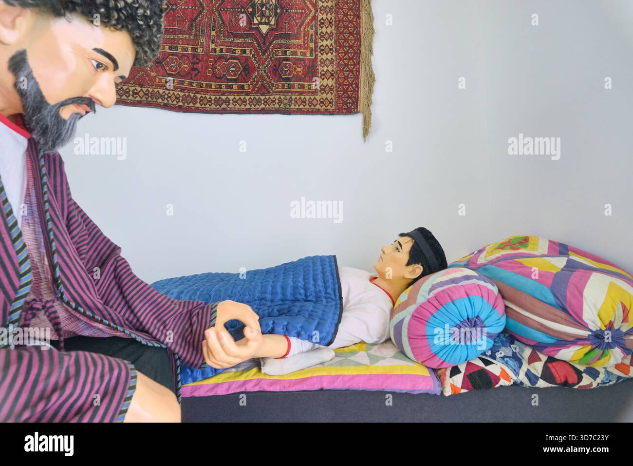 Diorama ricreativo di un medico dell'era della via della seta che esamina un paziente. Al museo medico di Shergazi Khan Madrasa. A Itchan Kala, Khiva, Uzbekistan. Foto Stock