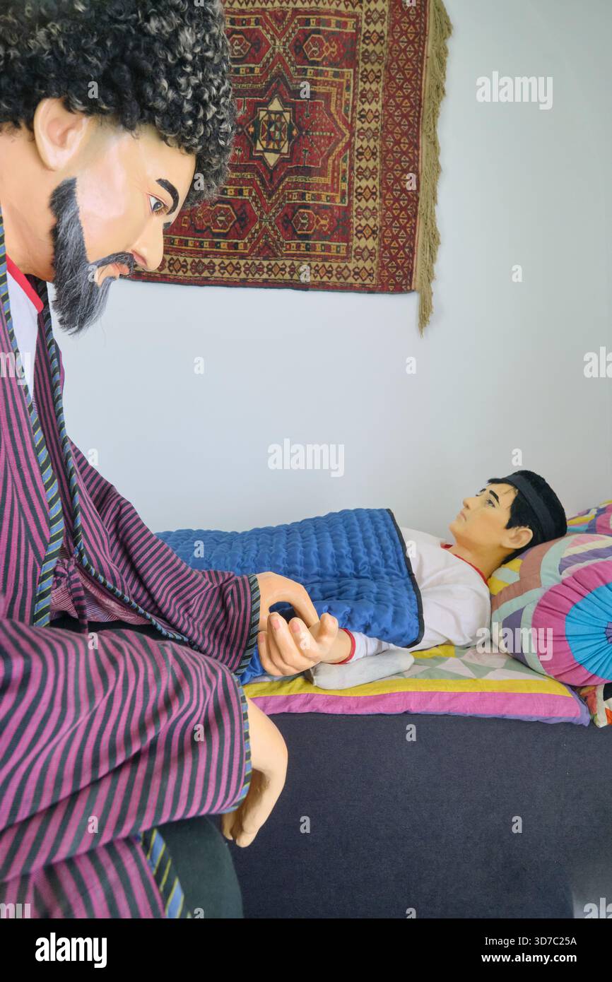 Diorama ricreativo di un medico dell'era della via della seta che esamina un paziente. Al museo medico di Shergazi Khan Madrasa. A Itchan Kala, Khiva, Uzbekistan. Foto Stock