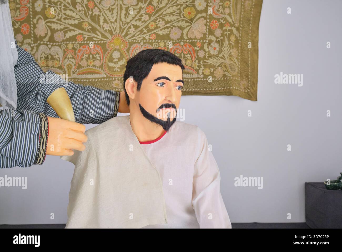 Diorama ricreativo di un medico dell'era della via della seta che esamina un paziente. Al museo medico di Shergazi Khan Madrasa. A Itchan Kala, Khiva, Uzbekistan. Foto Stock