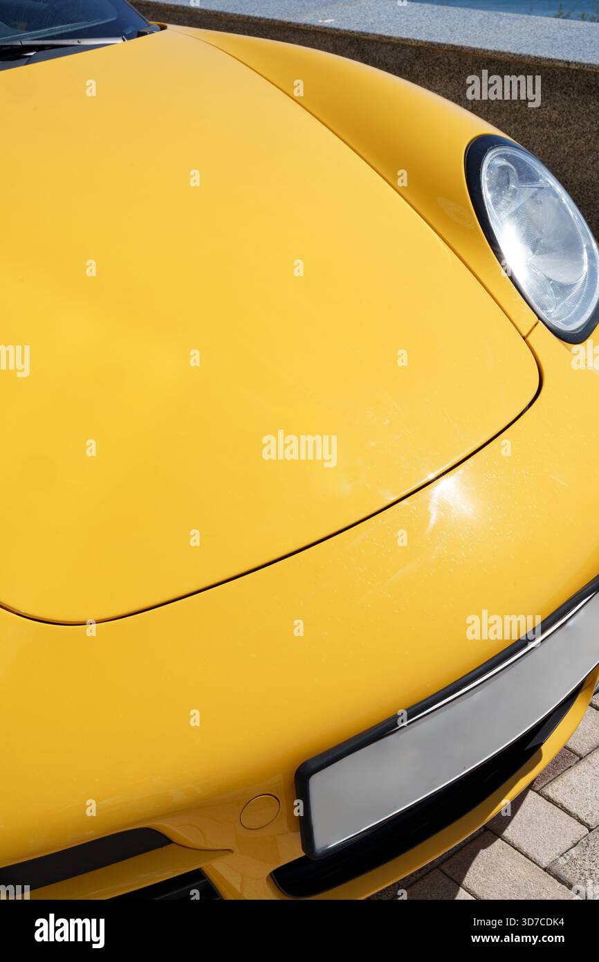 Auto sportiva di colore giallo brillante parcheggiata in una giornata di sole vicino a una zona a bordo piscina Foto Stock