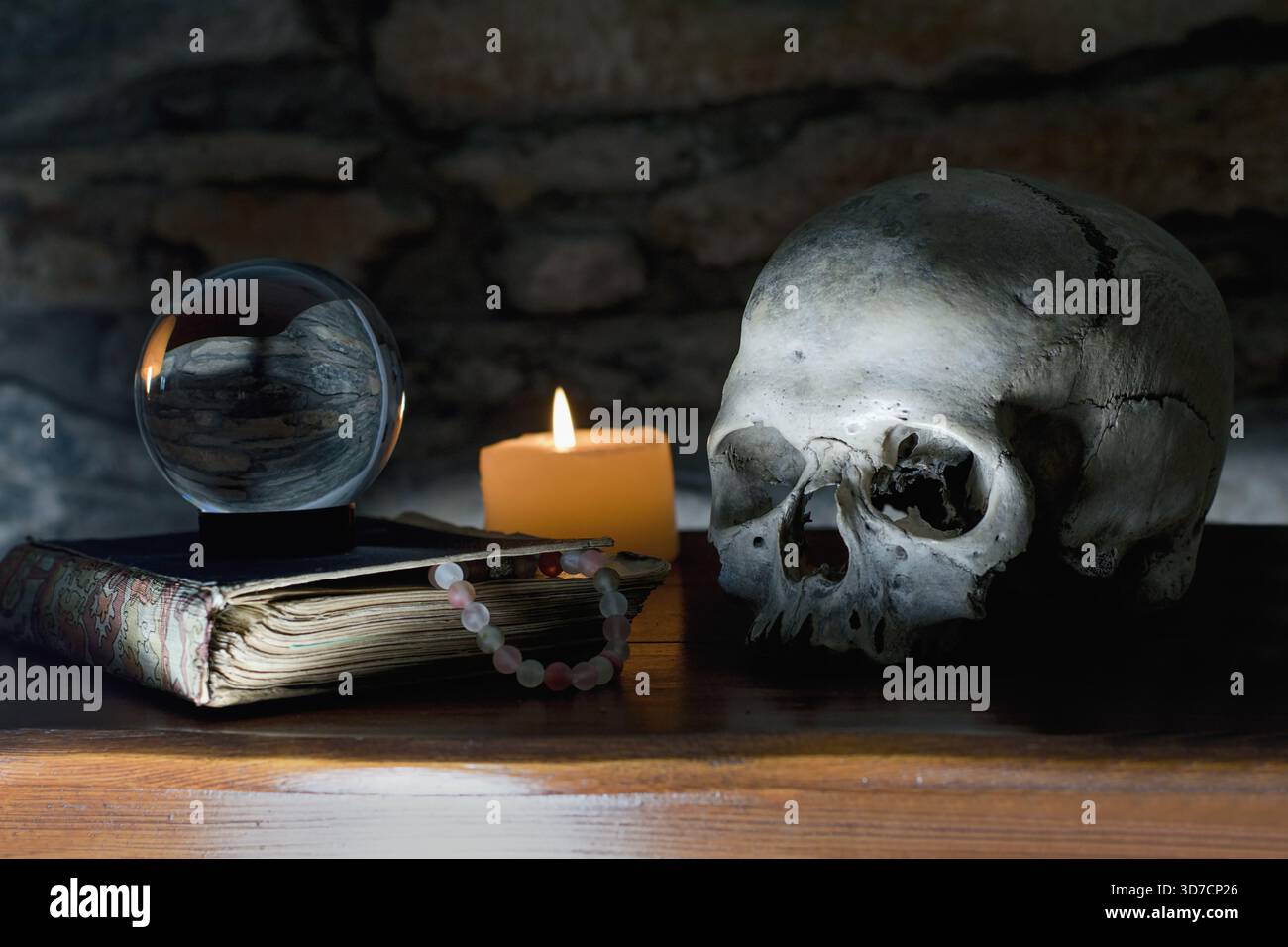 Reliquie rituali mistiche occulte: Teschio umano, candela, sfera di cristallo, vecchio libro e ragno Foto Stock