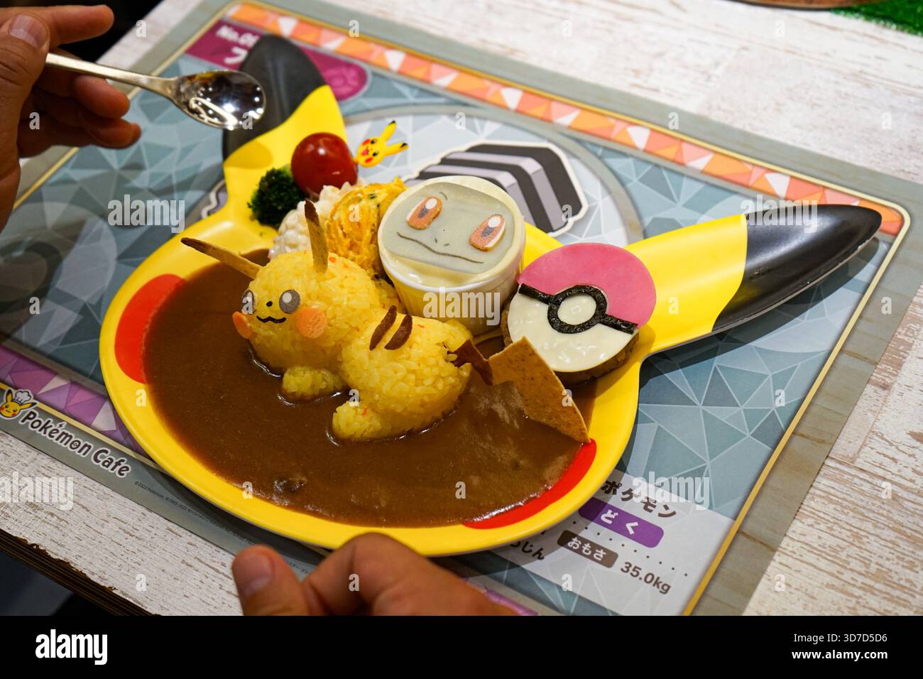 Il turista usa un cucchiaio per mangiare il piatto Pikachu e Squirtle's Best Friends Forever Curry Plate a Nihonbashi, Tokyo, Giappone Foto Stock