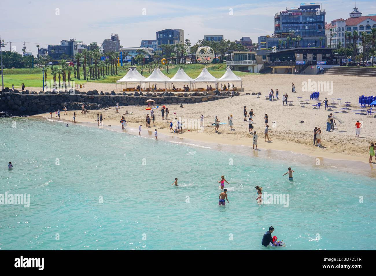 La folla di turisti nuota nell'acqua dell'oceano presso la famosa spiaggia Hamdeok a Jeju City, Jeju Island, Corea del Sud Foto Stock