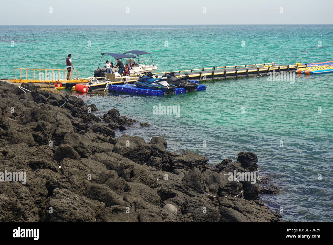 Le guide turistiche di Hamdeok Beach si trovano su un molo con i turisti che si imbarcano su una barca su una spiaggia rocciosa nella città di Jeju, l'isola di Jeju, Corea del Sud Foto Stock
