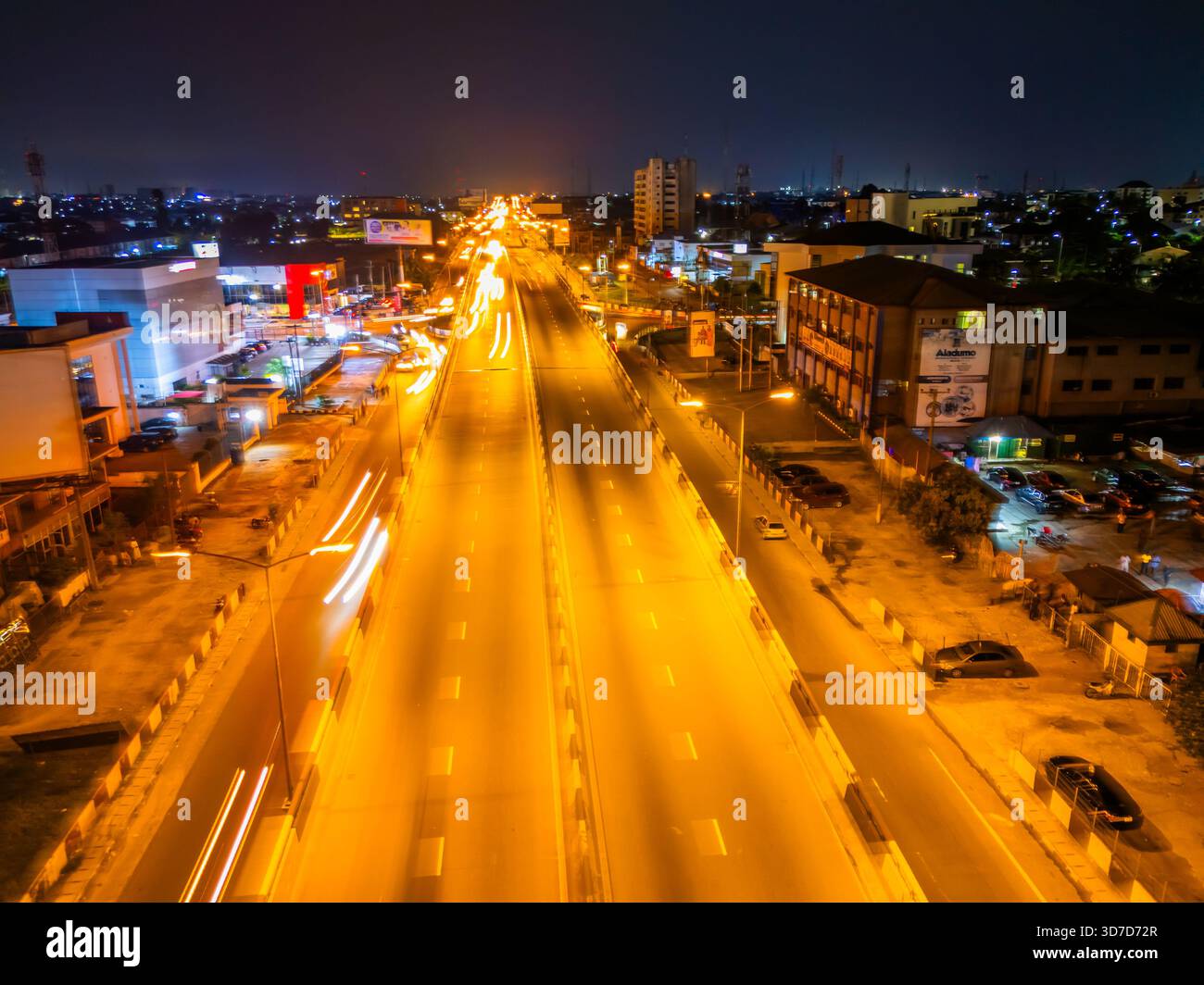 Veduta aerea del raccordo GRA, dove sentieri luminosi di fari si estendono attraverso Aba Road sotto il soffice bagliore dei lampioni, Port Harcourt, Rive Foto Stock