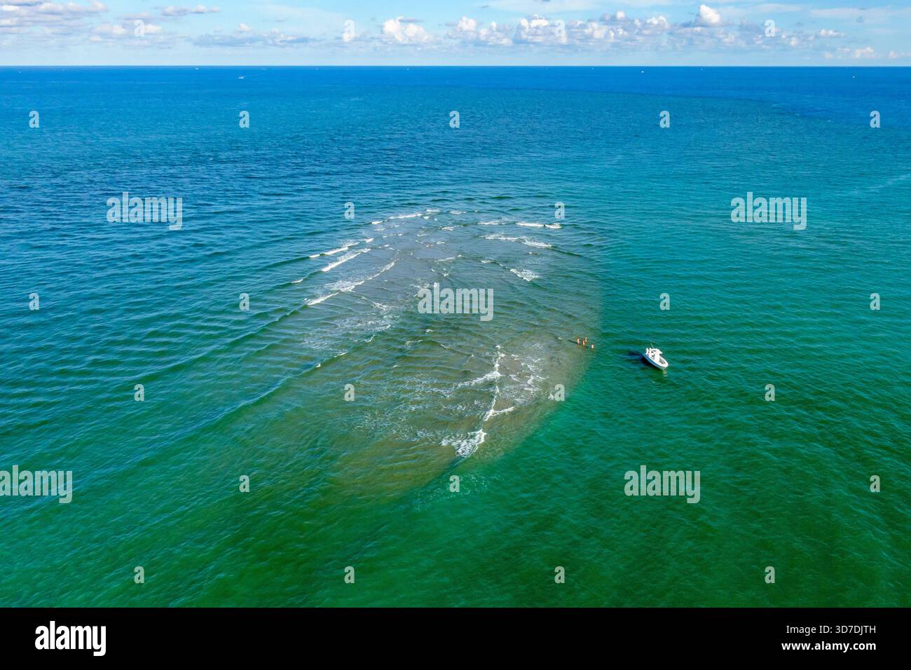 Vista aerea di una barca che naviga attraverso l'oceano con un contrasto sorprendente tra le acque blu e le fondali sabbiose, Giove, Florida, United Foto Stock