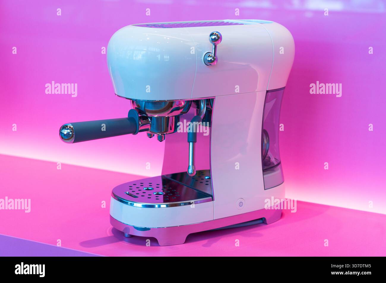 La moderna macchina da caffè si distingue per le sue linee eleganti e le finiture lucide, impreziosita da uno sfondo rosa brillante. Ideale per gli amanti del caffè Foto Stock