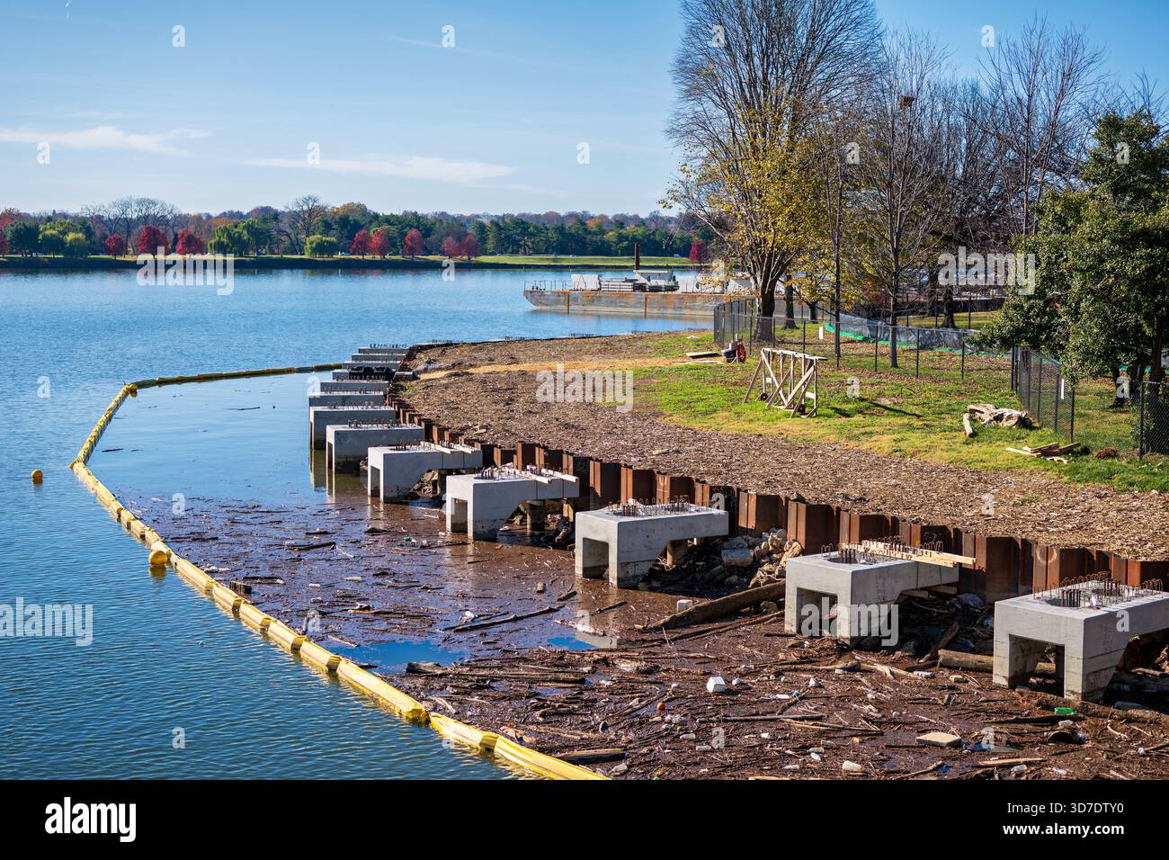 WASHINGTON DC - il progetto Tidal Basin Seawall Construction Project è stato inaugurato il 24 novembre 2025 e presenta nuove fondamenta in cemento, pali in lamiera e un boom giallo lungo la costa del fiume Potomac. Questo vasto progetto del National Park Service mira a riparare e sollevare le dighe deteriorate intorno al bacino delle maree e al West Potomac Park. I lavori affrontano le inondazioni croniche e il cedimento causati dall'innalzamento del livello del mare. La vista è da Inlet Bridge, che guarda oltre il fiume Potomac verso Arlington, Virginia. Foto Stock