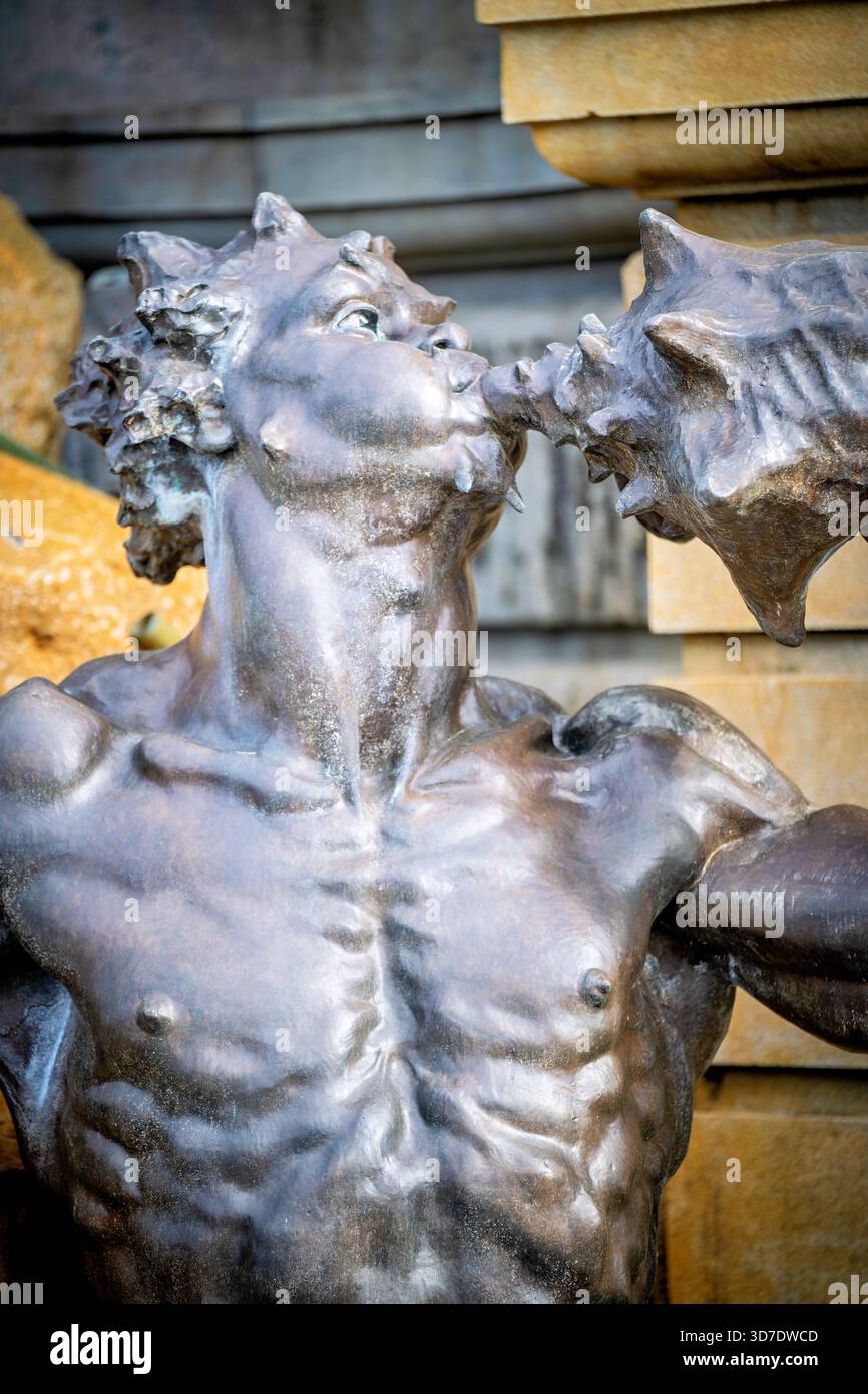 WASHINGTON DC - Una scultura in bronzo di Tritone, parte della Court of Nettuno Fountain presso la Library of Congress Thomas Jefferson Building, è vista soffiare una conchiglia come un beccuccio d'acqua. Questa figura di 3,7 metri è uno dei due Tritoni che fiancheggiano la scultura centrale di Nettuno. Progettata da Roland Hinton Perry e fusa dalla Henry-Bonnard Bronze Company, la fontana semicircolare larga 50 piedi (15 metri) è stata completata nel 1898. Si tratta di un risultato determinante della scultura Beaux-Arts americana, ispirata alla Fontana di Trevi a Roma. La fontana rimane operativa oggi, salutando i visitatori al Jefferson Foto Stock