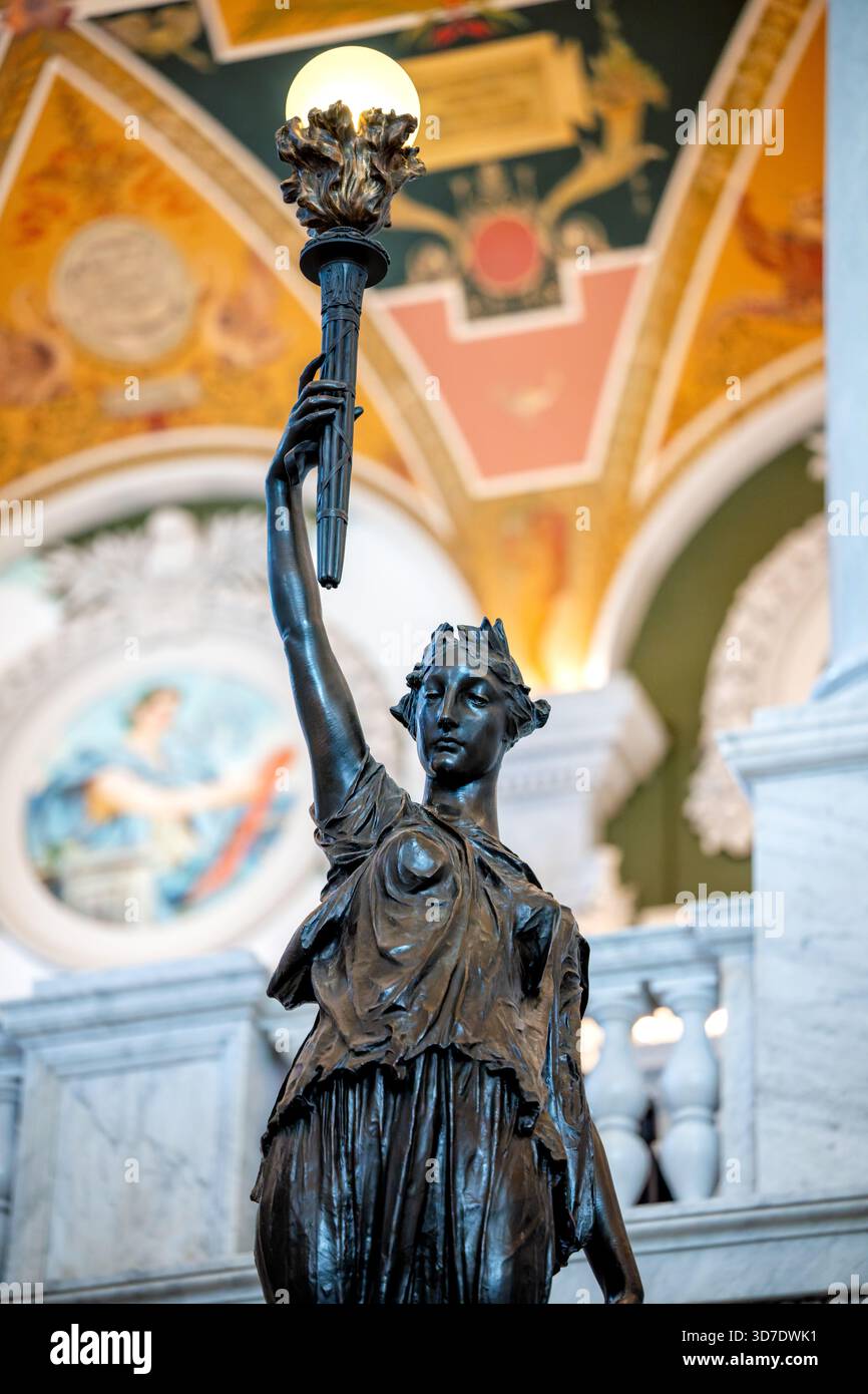 WASHINGTON DC - Una statua in bronzo del portabandiera, scolpita da Philip Martiny, si trova alla base di una delle imponenti scalinate della Library of Congress Jefferson Building. La figura femminile indossa i classici tendaggi e possiede una torcia di conoscenza, che funziona anche come una lampada. Queste statue, insieme ai putti in marmo di Marminino raffiguranti occupazioni e continenti sulle ringhiere delle scale, impreziosiscono la sala grande. Il Jefferson Building, completato nel 1897, è il più antico degli edifici della Biblioteca del Congresso. Foto Stock