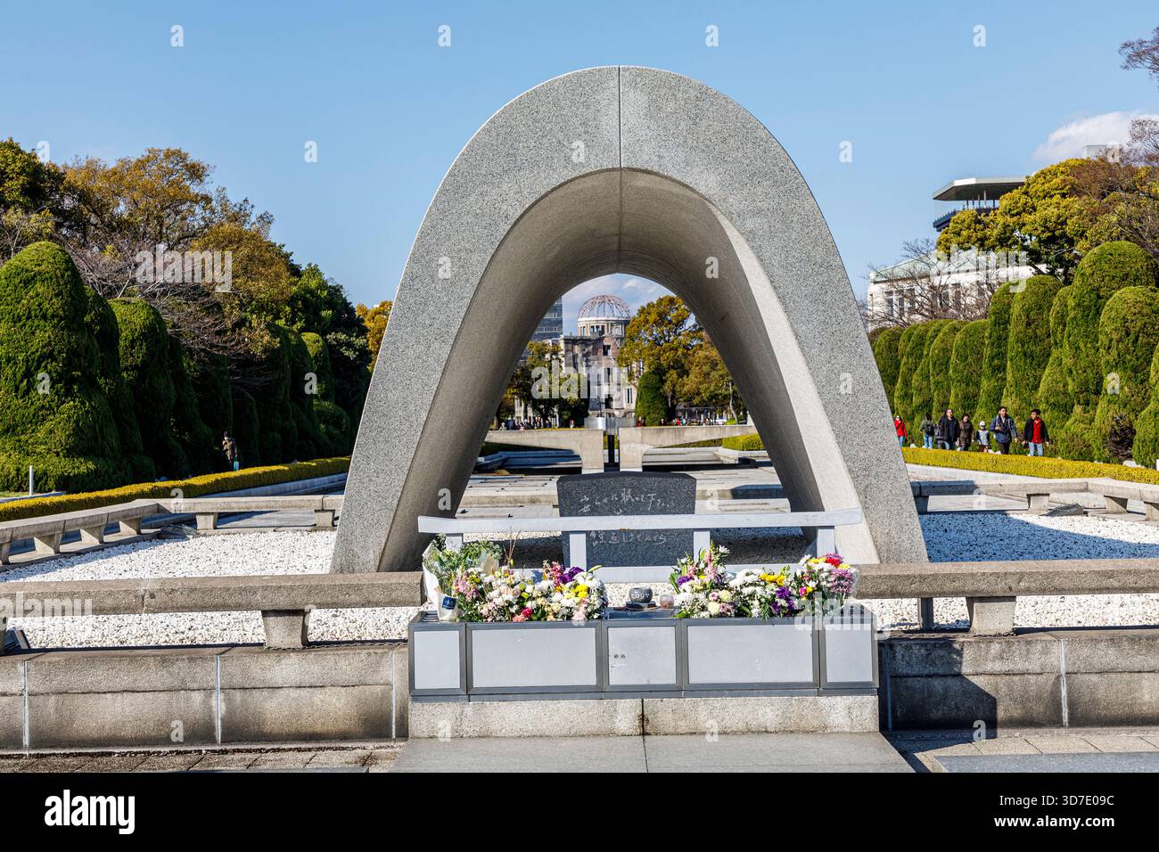 Hiroshima Peace City Monument Cenotaph per le vittime della bomba atomica con la cupola distrutta in lontananza, Memorial Park, Hiroshima, Giappone Foto Stock