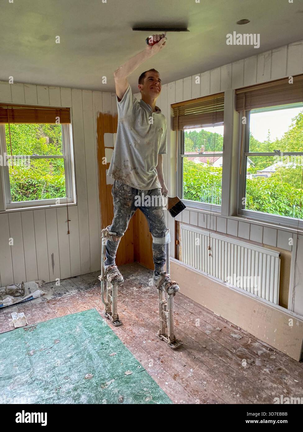 Un intonaco che reintonaca un alto soffitto con l'aiuto di intonacare palafitte da passeggio, Brtain Foto Stock