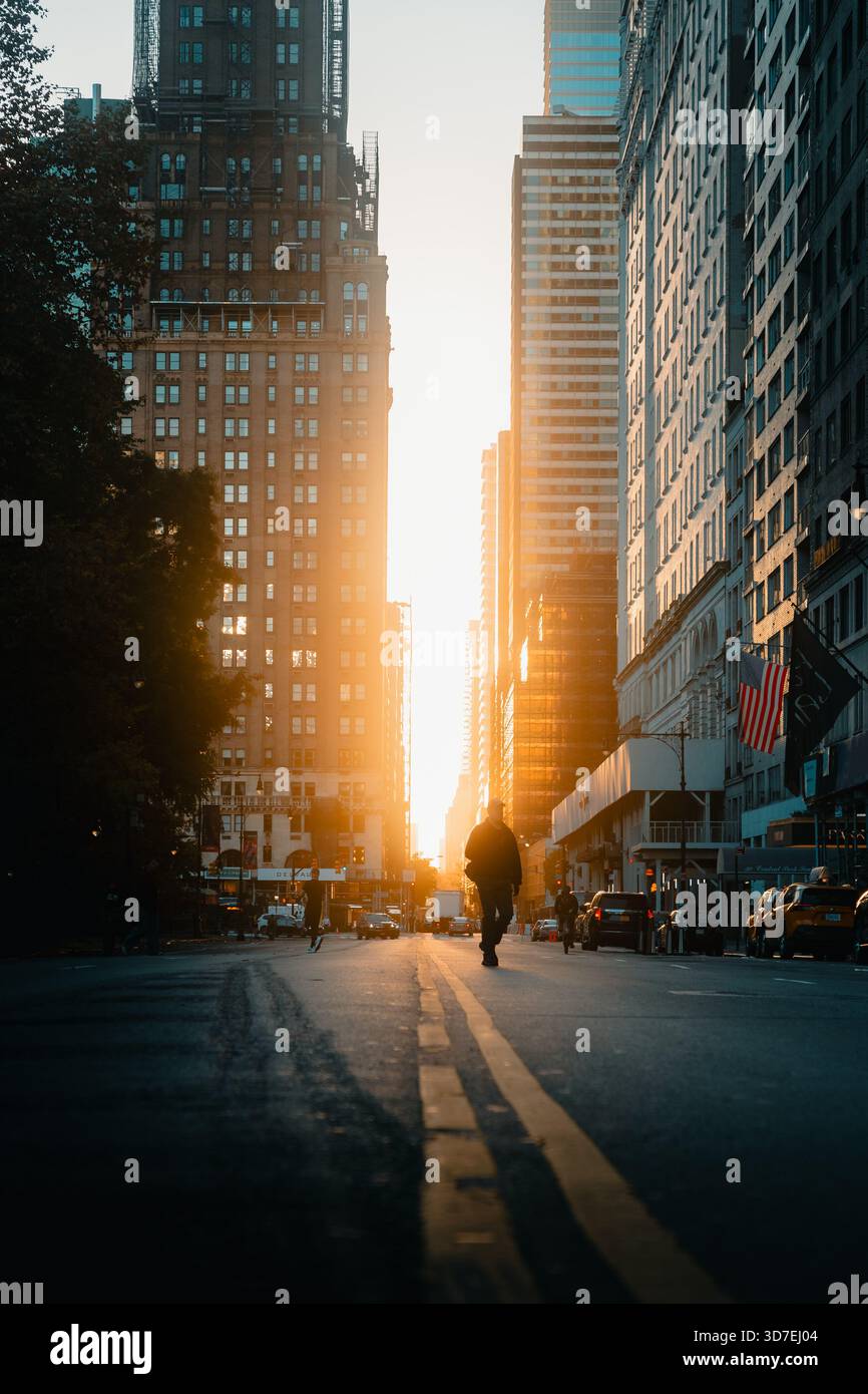 Uomo che cammina attraverso una strada di New York con uno sfondo illuminato Foto Stock