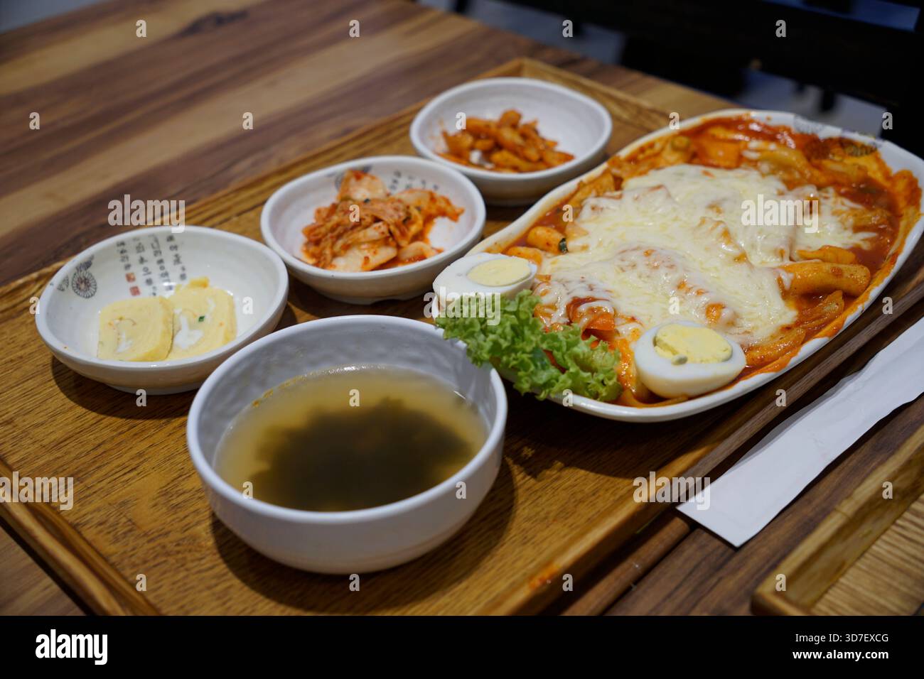 Il Cheesy tteokbokki viene servito con kimchi e contorni Foto Stock