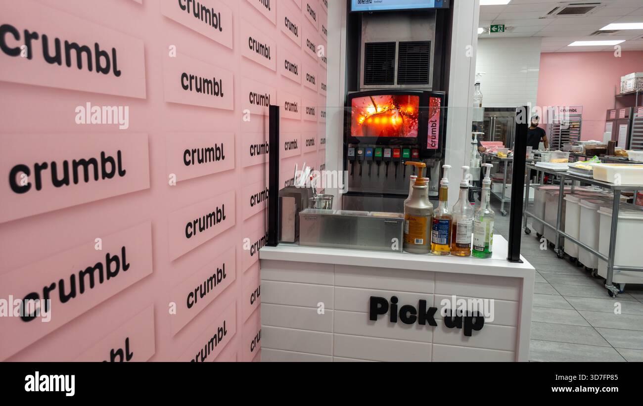 Crumbl Cookies Store interno con marchio rosa, banco di raccolta, macchina per bibite e cucina sullo sfondo. - Immagine stock catturata con smartphone