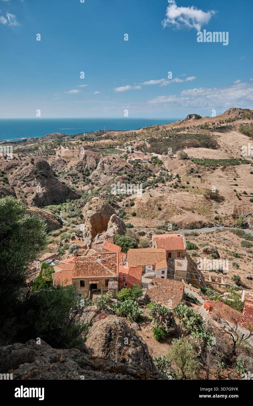 Panorama mediterraneo con tetti, colline rocciose e mare nel sud Italia, vicino al paese di Pentedattilo. Foto Stock