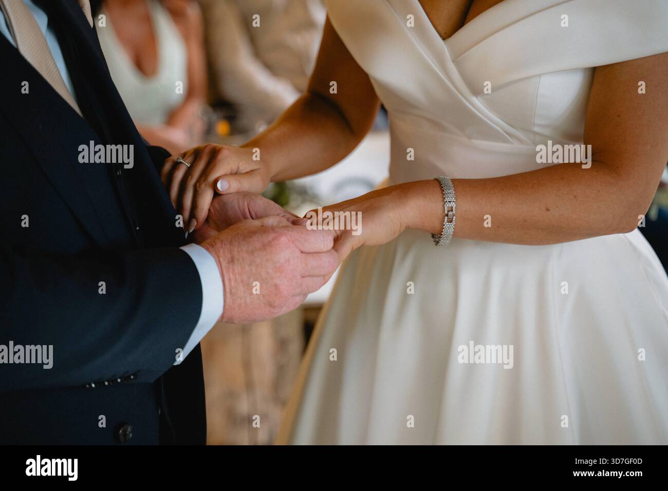 Un uomo e una donna si sposano. L'uomo indossa un vestito e la donna indossa un vestito bianco. Indossano entrambe le fedi nuziali Foto Stock