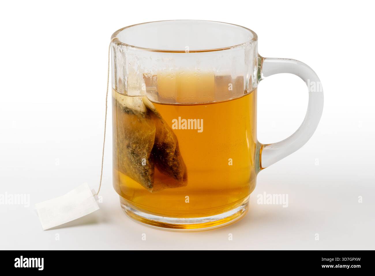 Rilassante tè digestivo alle erbe con camomilla e liquirizia in un sacchetto filtrante da immergere in acqua bollente in una tazza di vetro isolata su bianco con clippin Foto Stock