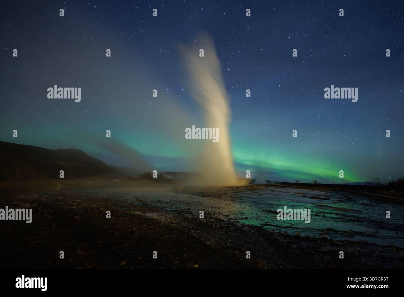 Una foto del geysir che eruttava nel cerchio d'oro dell'Islanda sotto una forte aurora Foto Stock