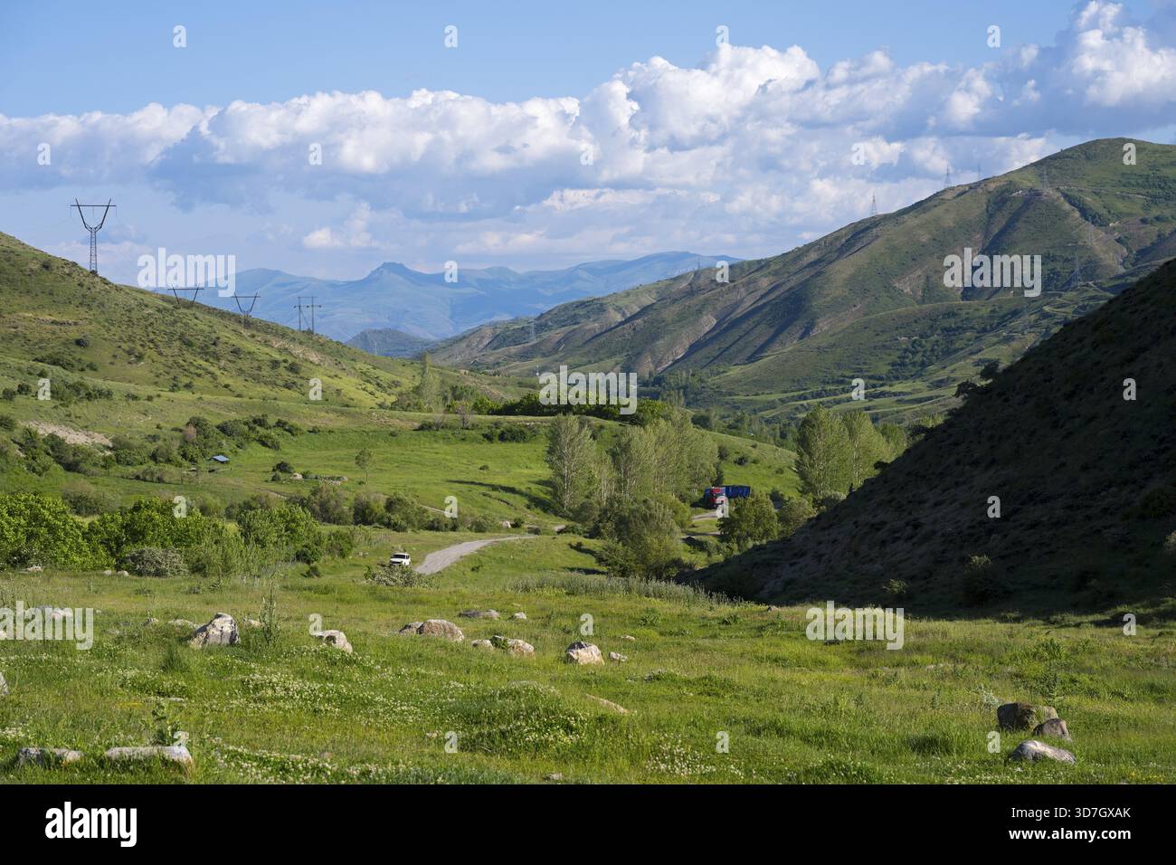 Valle con paesaggio verde, linee elettriche, circondata da montagne e sotto un cielo nuvoloso, paesaggio da sud verso il passo Vardenyats o il passo Selim, Foto Stock