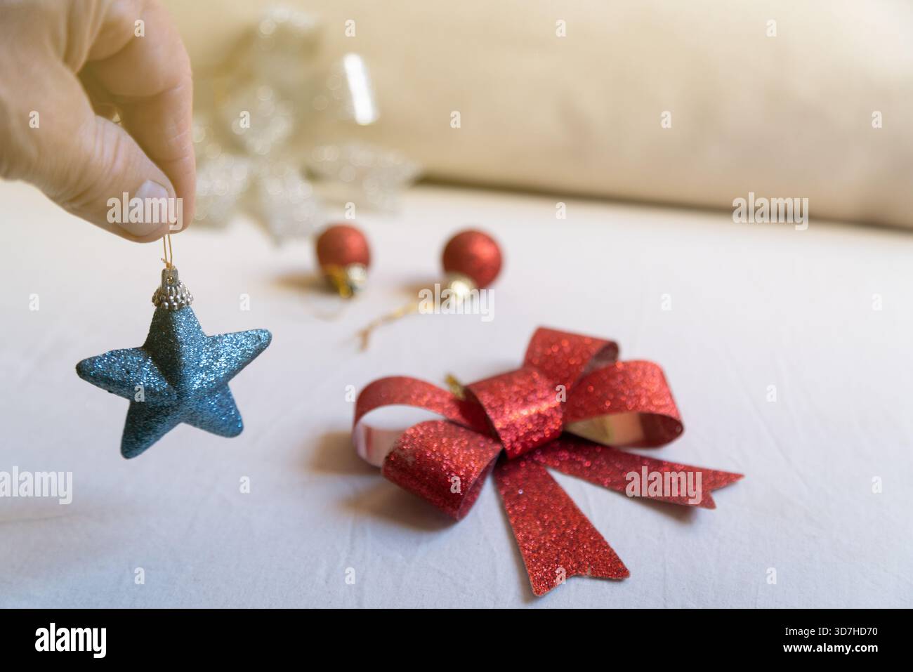 Mano che regge l'ornamento natalizio con stella glitter blu Foto Stock