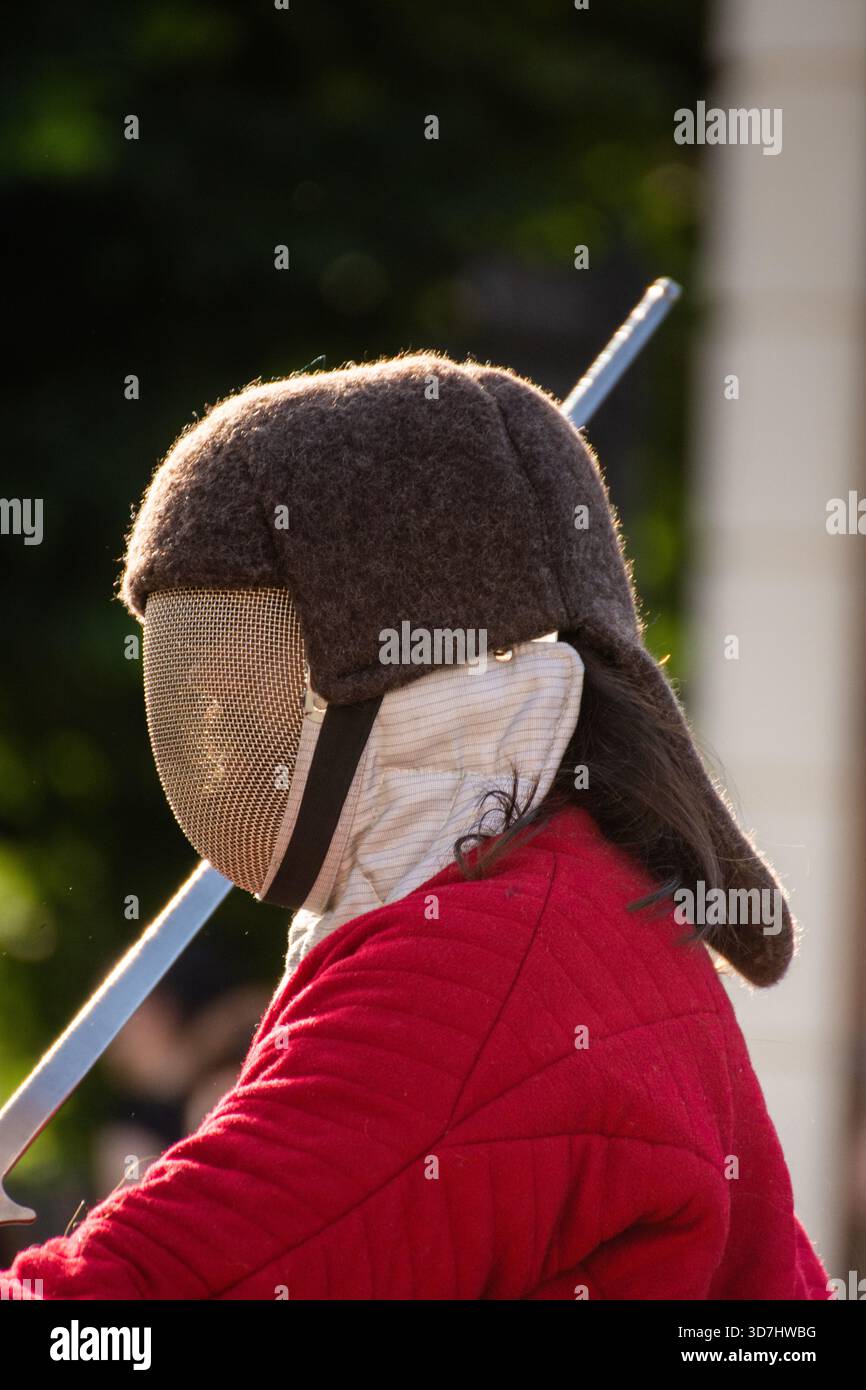 una persona che indossa dispositivi di protezione per la recinzione, una maschera protettiva con una rete metallica per il viso Foto Stock