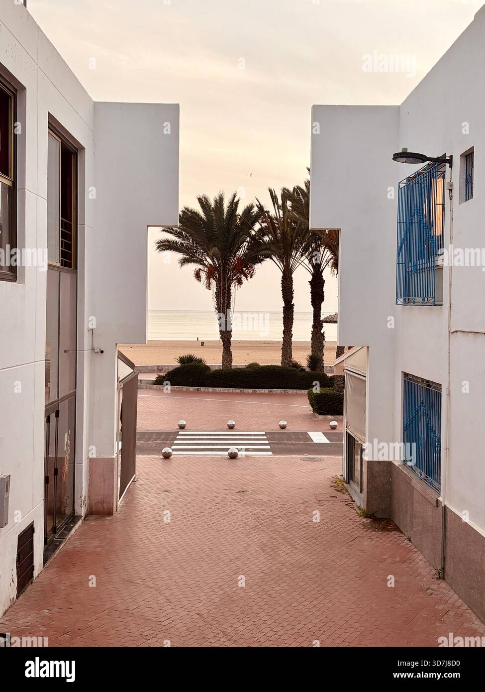 Moderno passaggio pedonale che conduce ad una spiaggia costeggiata da palme al tramonto ad Agadir - Immagine stock catturata con smartphone