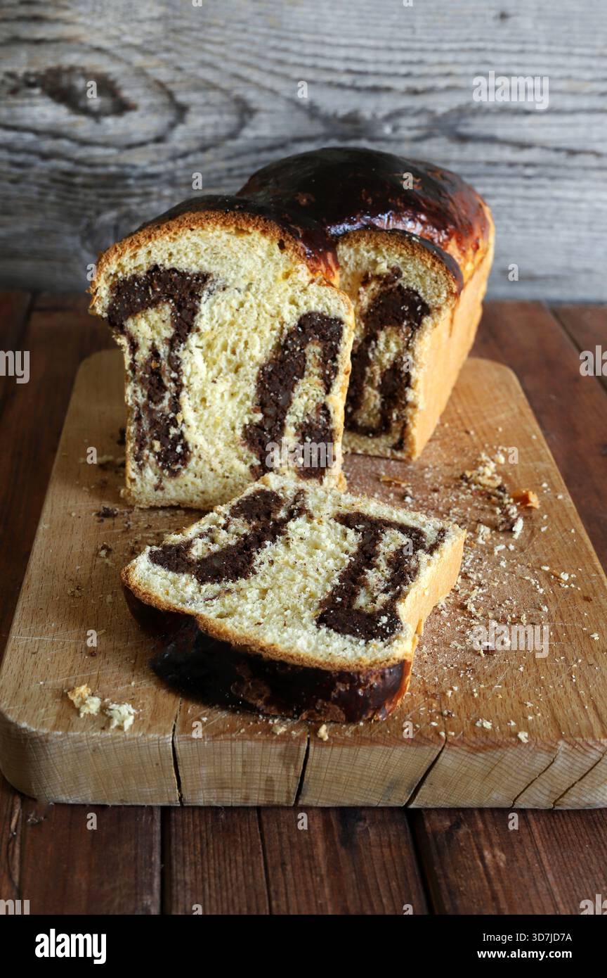 Cozonac, dolce tradizionale rumeno di Pasqua o di Natale. Tagliare il pane dolce su un tagliere di legno. Vacanze gastronomiche dell'Europa orientale. Foto Stock